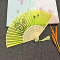 Lime green Chinese folding fan with black floral pattern, bamboo ribs and matching tassel - Butterfly Flying Flower - Yellow Green