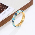 Brazalete bohemio dorado con patrones rectangulares de esmalte azul en una bandeja de madera - Oro & Azul Arena