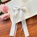 Elegant white satin ribbon hair clip with long streamers on a vintage book backdrop - White