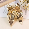 Eleganter goldener Haarclip in Schleifenform mit Hochglanz-Finish auf Vintage-Hintergrund - Gold