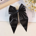 Eleganter schwarzer Haarschleifenclip mit Metallic-Finish und langen Bändern auf Dekoration - Schwarz