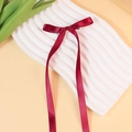 Elegant deep red satin bow hair clip with long ribbons on white textured plate - Burgundy