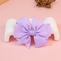 Purple grosgrain ribbon bow accessory displayed on a white stand with a pink background - Purple