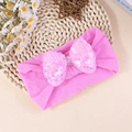 Bandeau élastique rose pour bébé avec un grand nœud en paillettes sur tapis tressé - Rose