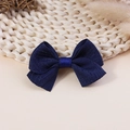 Detail of a navy blue ribbon bow hair clip with textured fabric on a rustic straw mat - Navy Blue Ribbed Ribbon Style (#1)