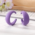 Détail de boucles d'oreilles en C violet mat sur fond texturé avec de la soie et des fleurs - Violet foncé