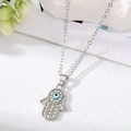 Dettaglio del ciondolo Mano di Hamsa argentato con strass brillanti e occhio blu centrale - Collana Mano di Fatima Argento Piccolo Occhio Verde Bianco