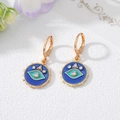 Detailaufnahme goldener Creolen mit blauem Emaille-Auge und glänzenden Zirkonia-Steinen - Blaue Creolen