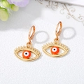 Macro shot of gold evil eye hoop earrings with colorful enamel and lash details - Orange And White
