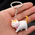 Schattige witte hars kat sleutelhanger met roze strik en gestreepte staart vastgehouden in de hand - Geelstaart Dikke Kat