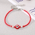Detail of red bead bracelet with evil eye charms and white pearls on gray surface - Red Beads and Pearl with Red Eye