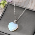 Detail of a heart-shaped opal pendant necklace on a refined grey jewelry display box - Holographic Color
