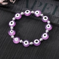 Vue détaillée des perles œil grec mauves et perles argentées sur un bracelet élastique - Violet