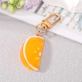 Detail view of a realistic orange slice keychain with golden lobster clasp on a flat lay - Orange Slice Keychain