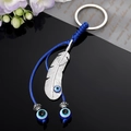 Portachiavi etnico con piuma d'argento, occhio di Allah e nappine di perline blu eleganti - Occhio di Piuma