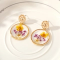 Macro shot of handmade gold earrings featuring real dried flowers in transparent resin - Yellow & White Flowers