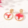 Macro detail of round gold resin earrings featuring real vibrant pink dried flowers - Single Red Flower