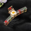 Makro-Detail einer transparenten Harz-Haarklammer mit echtem Gänseblümchen und Trockenblumen - Weißes Gänseblümchen Rote Blume