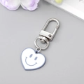 Dettaglio portachiavi a cuore con faccina blu e bordo viola chiaro su sfondo - Blu Bianco Cuore Sorriso