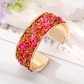 Detail van een bohemien gouden open armband met roze steentjes en amberkristallen - Rozerode Steen Armband