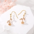 Detailed view of golden rose earrings with zircons on a white stone pedestal - Rose