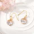 Detailed macro shot of gold celestial earrings with moon and stars on a white plate - Round Star & Moon
