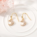 Detailed macro view of gold crescent moon earrings featuring shimmering clear rhinestones - Star and Moon