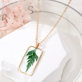 Détail macro du collier carré doré avec une véritable feuille verte sertie de résine - Brin d'herbe verte (Article 1)