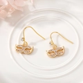 Detailed view of mask-shaped earrings with inlaid crystals on a white ceramic plate - Mask