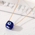 Detailansicht eines blauen Harzwürfel-Anhängers mit bösem Blick an einer feinen Goldkette - Dunkelblau