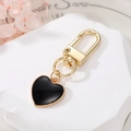 Detailed view of heart-shaped black enamel keychain with golden metal clasp on marble base - Black (K60)