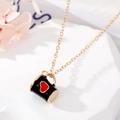 Vue macro d'un pendentif tasse en émail noir avec cœur rouge sur chaîne dorée - Gobelet Noir Coeur Rouge