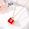 Détail macro du collier doré avec pendentif mug émaillé rouge et cœur sur marbre blanc - Gobelet Rouge Coeur Rose