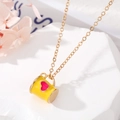 Détail du pendentif tasse en émail jaune avec cœur rose et chaîne en or sur pierre - Gobelet Jaune Coeur Rose Rouge