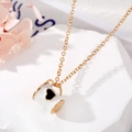 Vue détaillée d'un collier doré avec pendentif mug blanc à cœur posé sur une pierre - Gobelet Blanc Coeur Noir