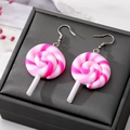 Macro shot of pink and white spiral lollipop earrings on a black textured jewelry box - Pink White Lollipop