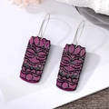 Close-up of African Tiki style acrylic earrings in magenta with black face pattern - Purple