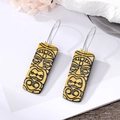 Detailed close-up of yellow African Tiki face earrings with black tribal patterns - Yellow