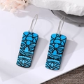 Detail of bright blue African Tiki mask earrings with tribal pattern on white stone - Blue