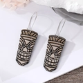 Ethnic Tiki mask dangle earrings with Polynesian totem design on white rock background - Brown