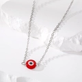 Macro-opname van rode hars boze oog hanger aan een zilveren ketting op witte stenen - Rood Oog