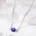 Macro shot of silver chain with dark blue resin evil eye pendant on white stone texture - Dark Blue Eye