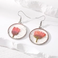 Macro view of silver round earrings with pink dried flowers and foil in transparent resin - Pink