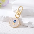 Detailansicht von goldenem Hamsa-Hand und blauem bösem Auge Anhänger auf weißem Marmor - Goldene Hamsa-Hand