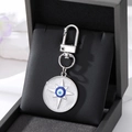 Close-up of silver evil eye keychain with blue enamel star detail on black leather box - Silver Shooting Star