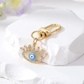Goldener Evil Eye Schlüsselanhänger mit Emaille und Kristallen auf Marmorstein - Blaues Wimpernauge