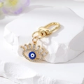 Close-up of golden Evil Eye keychain with blue enamel and sparkling white rhinestones - Dark Blue Eyelash Eye