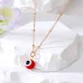 Golden necklace with red Evil Eye bead pendant hanging on a white geometric stone base - Red