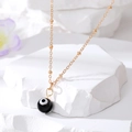 Golden Evil Eye pendant necklace with beaded chain on a white textured stone base - Black