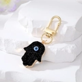 Detail of Hamsa Hand keychain with Evil Eye symbol and gold clip on white stone - Black Hamsa Hand